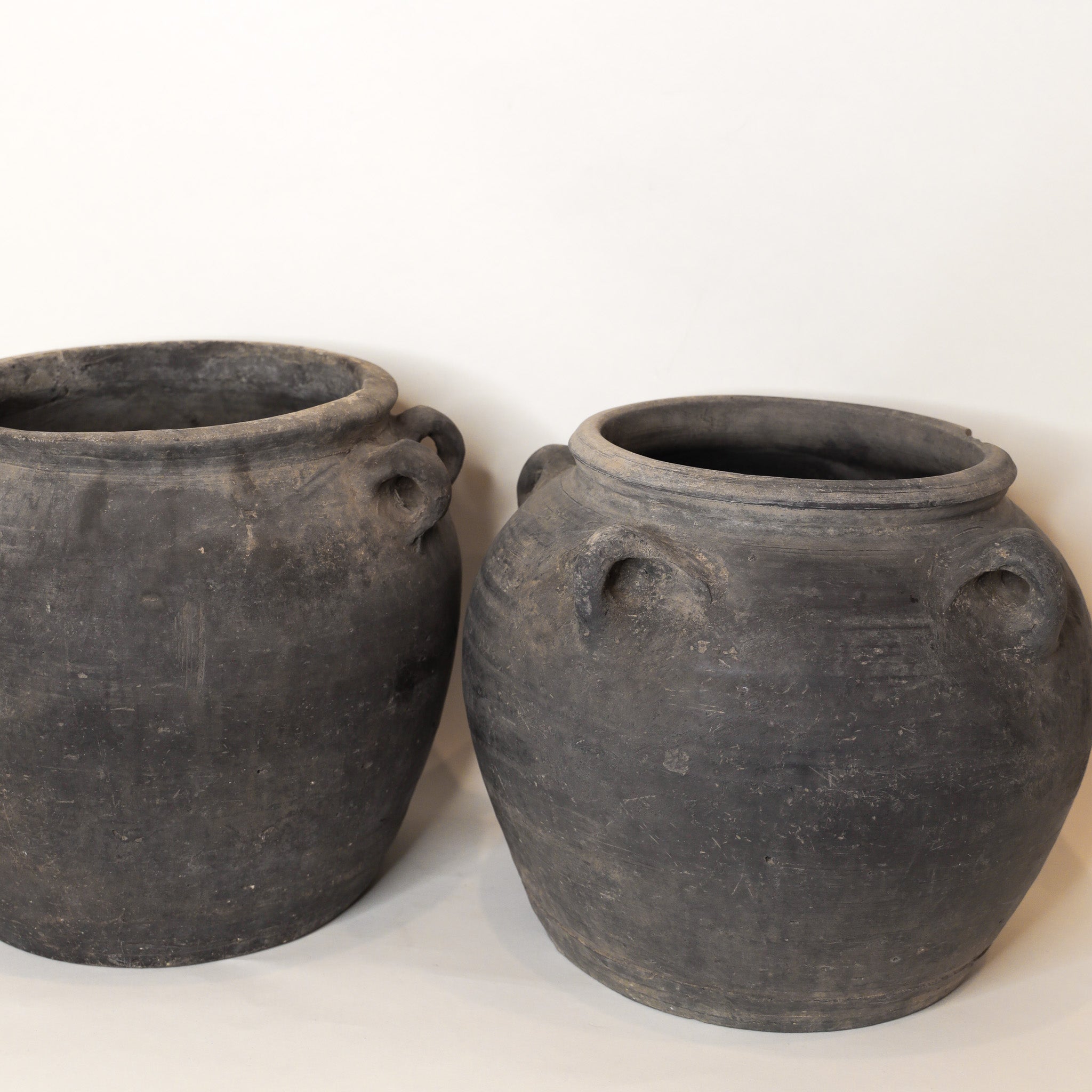 Two black earthen pots on a white background