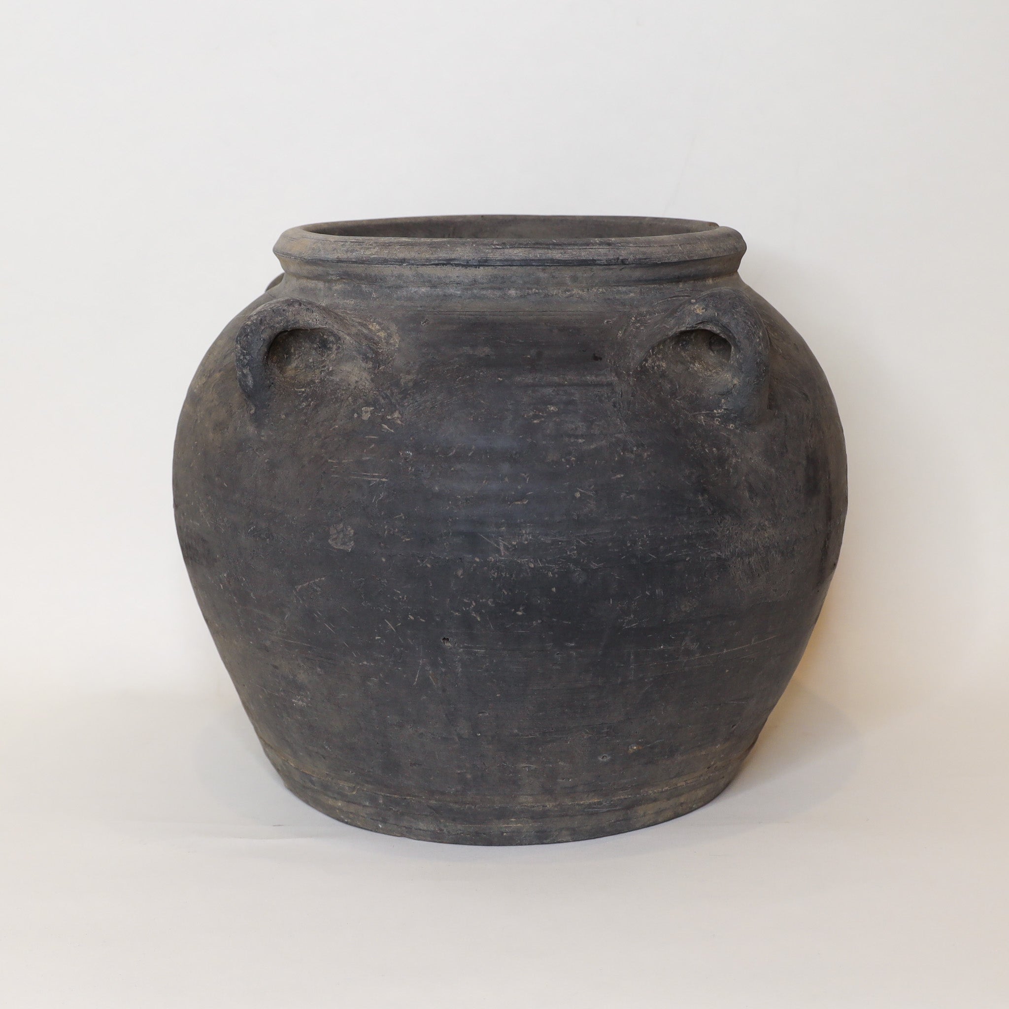 Black ceramic jar with four handles on a white background