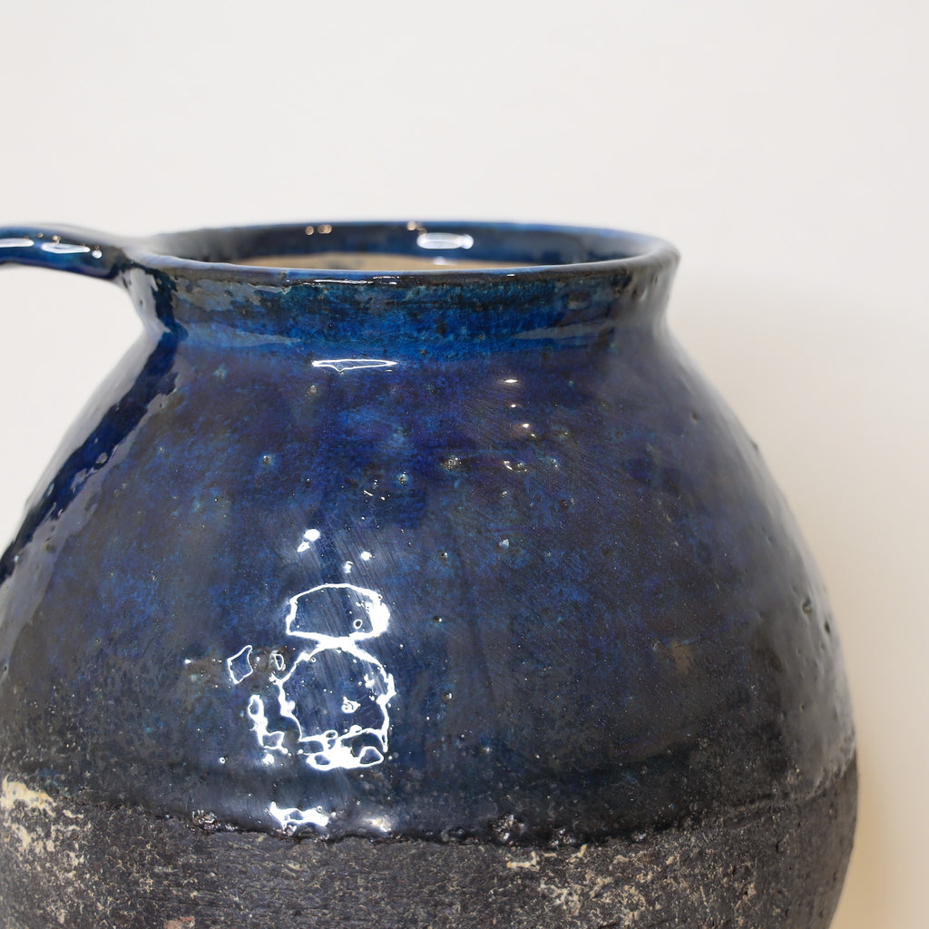 Blue ceramic pitcher vase on a light background