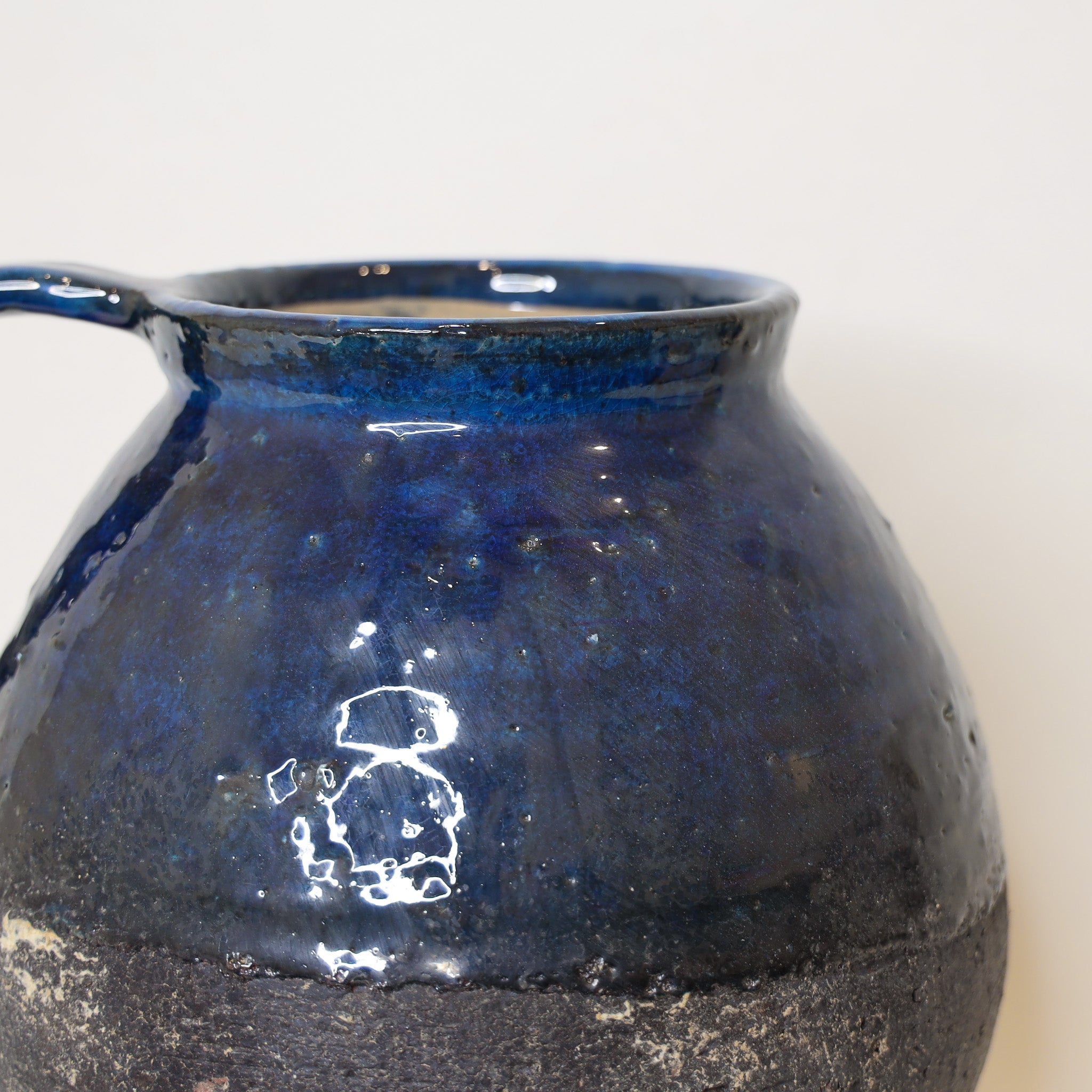 Blue ceramic pitcher vase on a light background